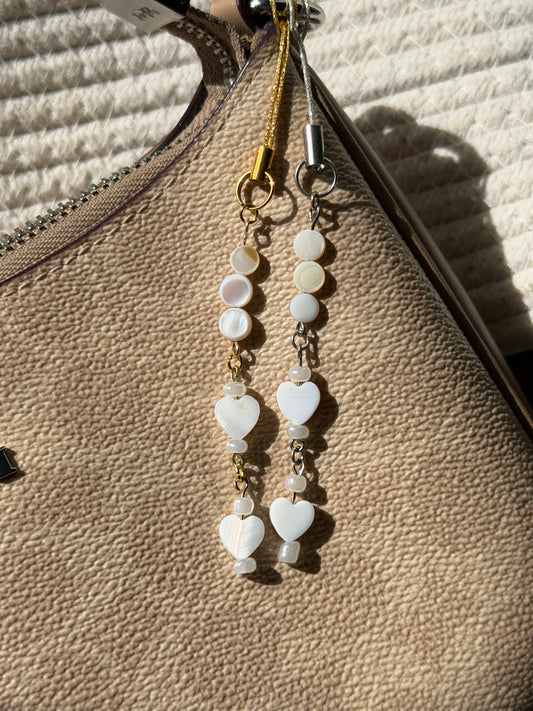 Heart-shaped beaded earrings on a textured beige surface
