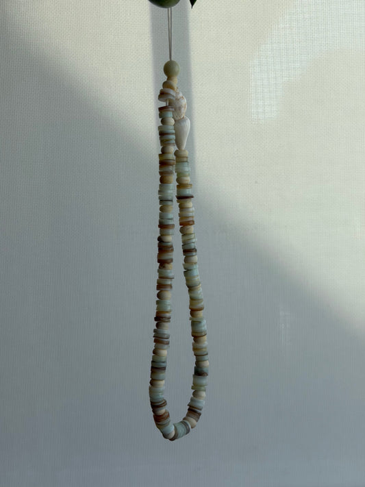 String of small, multicolored beads hanging against a light background